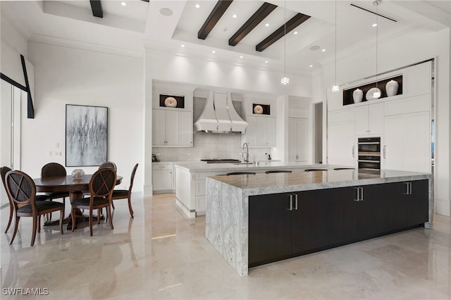 kitchen featuring premium range hood, a spacious island, a towering ceiling, marble finish floor, and decorative backsplash