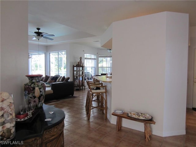620 Mirror Lakes Falls Ct, Lehigh Acres, FL 33974 - living room featuring a tray ceiling, tile patterned flooring, a ceiling fan, and baseboards