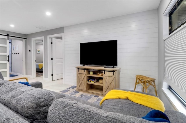 living room featuring wood walls, a barn door, and recessed lighting