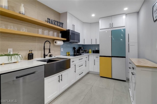 kitchen featuring dishwasher, freestanding refrigerator, light countertops, open shelves, and a sink