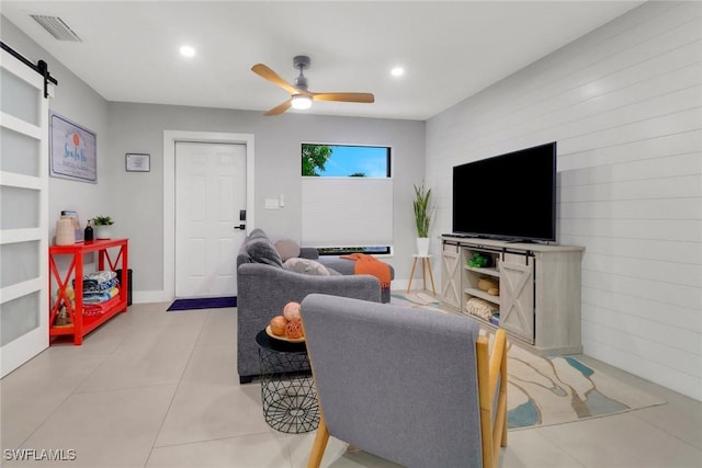 living area featuring light tile patterned floors, a barn door, visible vents, a ceiling fan, and recessed lighting