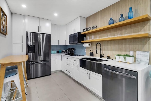 kitchen featuring open shelves, stainless steel appliances, light countertops, decorative backsplash, and a sink