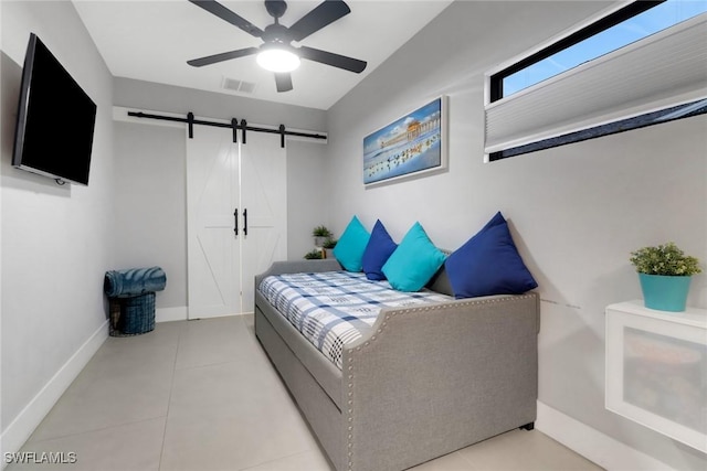 bedroom featuring tile patterned flooring, a barn door, visible vents, and baseboards