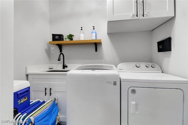 clothes washing area with washing machine and dryer, cabinet space, and a sink