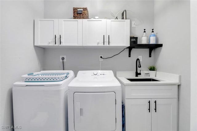 clothes washing area featuring cabinet space, washer and clothes dryer, and a sink