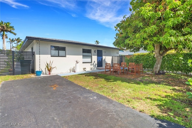 view of front of home featuring a patio area, fence, a front lawn, and stucco siding