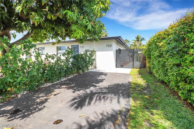 view of side of property with driveway, fence, and stucco siding