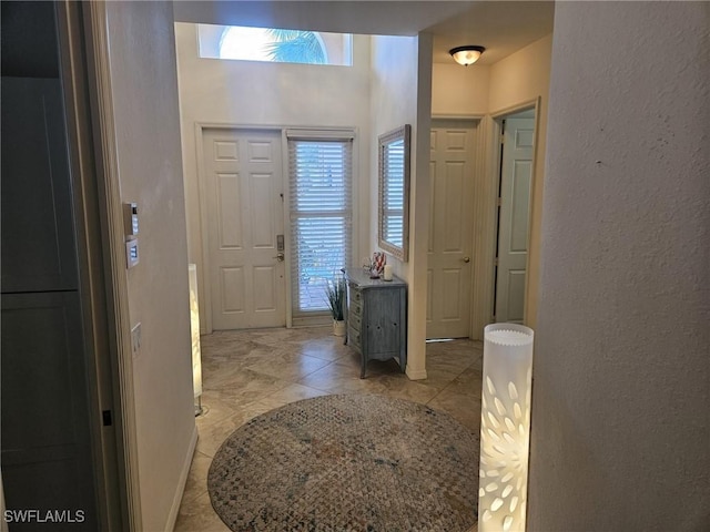 foyer entrance featuring baseboards and a textured wall