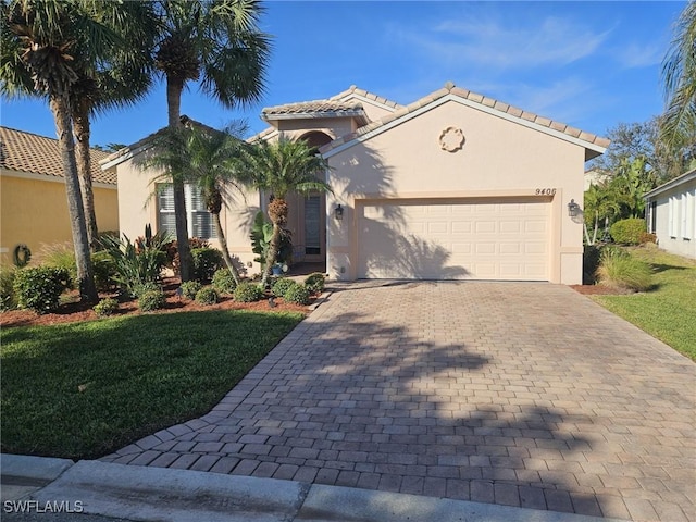 mediterranean / spanish house featuring a garage, a front yard, decorative driveway, and stucco siding