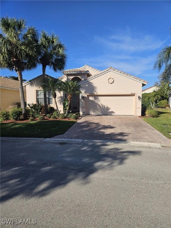 view of front of property with an attached garage, a tile roof, decorative driveway, and stucco siding