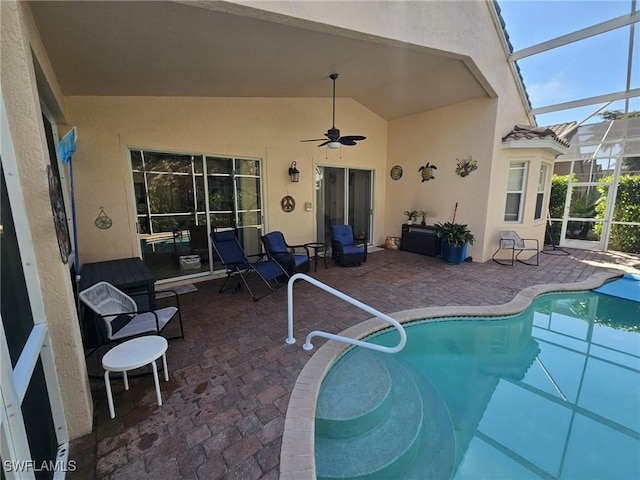 outdoor pool featuring glass enclosure, a patio, and ceiling fan