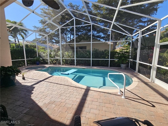 view of pool with a patio area, a pool with connected hot tub, and glass enclosure