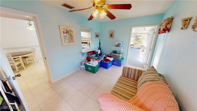 living area featuring ceiling fan, visible vents, baseboards, and light tile patterned flooring