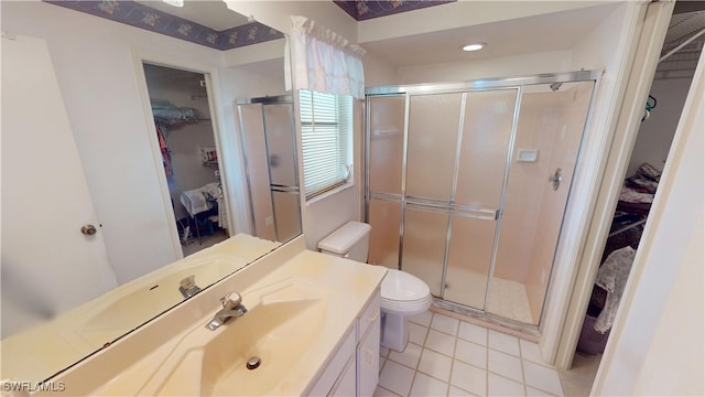 bathroom featuring tile patterned flooring, toilet, vanity, a spacious closet, and a stall shower