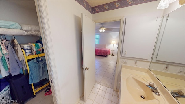 bathroom with a ceiling fan, a walk in closet, a sink, and tile patterned floors