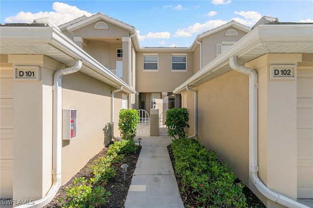 entrance to property with a garage, a gate, and stucco siding