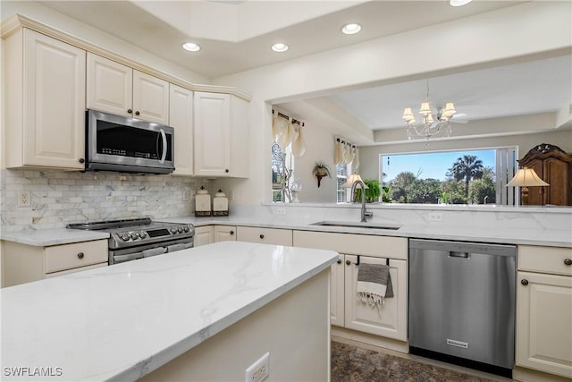 kitchen featuring backsplash, an inviting chandelier, appliances with stainless steel finishes, a sink, and light stone countertops