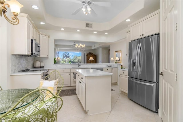 kitchen with visible vents, a raised ceiling, light countertops, stainless steel appliances, and a sink