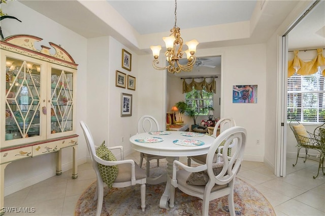 dining room featuring a chandelier, a raised ceiling, baseboards, and light tile patterned floors