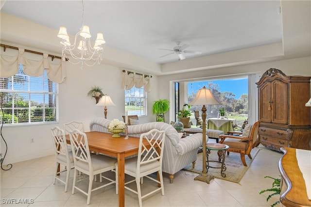 interior space featuring light tile patterned floors, baseboards, a tray ceiling, and ceiling fan with notable chandelier