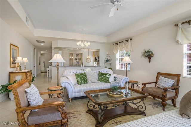 living area with light tile patterned floors, a raised ceiling, visible vents, and ceiling fan with notable chandelier