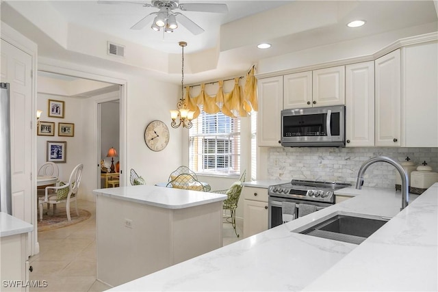 kitchen featuring visible vents, decorative backsplash, a raised ceiling, appliances with stainless steel finishes, and a sink