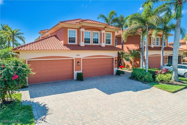 mediterranean / spanish home featuring a tiled roof, decorative driveway, and stucco siding