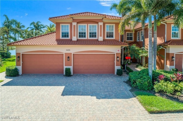 mediterranean / spanish-style home featuring decorative driveway, a tiled roof, and stucco siding