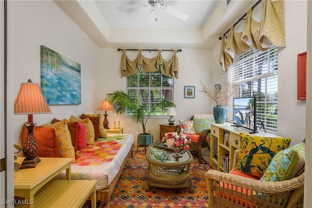 sitting room with a healthy amount of sunlight, visible vents, a raised ceiling, and a ceiling fan