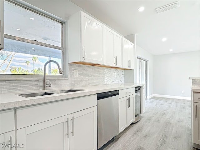 kitchen with a sink, visible vents, light countertops, stainless steel dishwasher, and backsplash