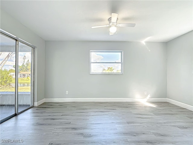 spare room featuring ceiling fan, baseboards, and wood finished floors