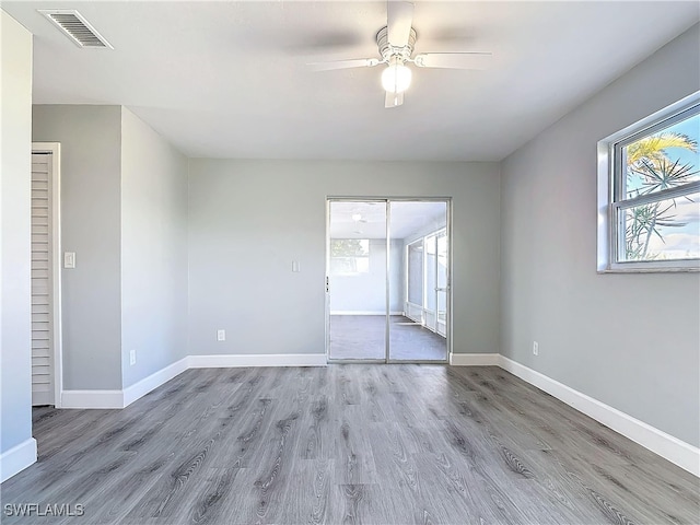 unfurnished room with visible vents, ceiling fan, baseboards, and wood finished floors