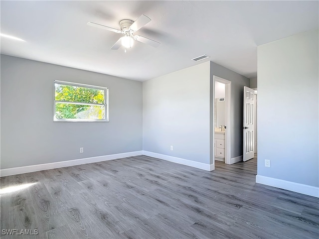 empty room with a ceiling fan, visible vents, baseboards, and wood finished floors