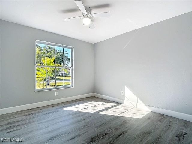 empty room featuring wood finished floors, a ceiling fan, and baseboards