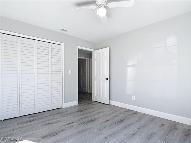 unfurnished bedroom featuring visible vents, a closet, baseboards, and wood finished floors