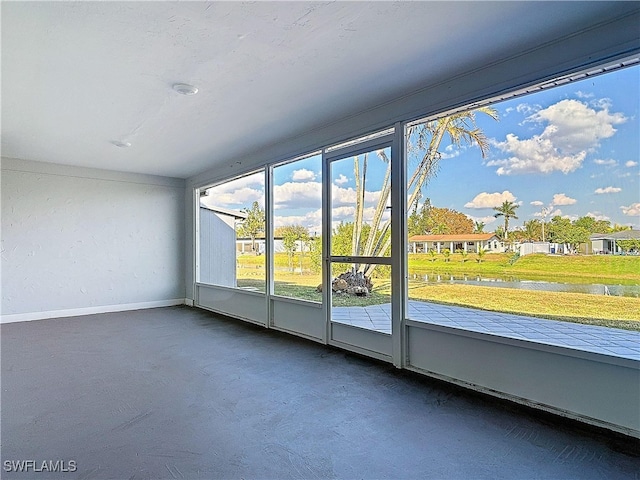 interior space with a water view, baseboards, and concrete flooring