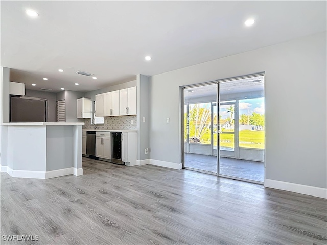 kitchen with light wood finished floors, tasteful backsplash, light countertops, visible vents, and dishwasher