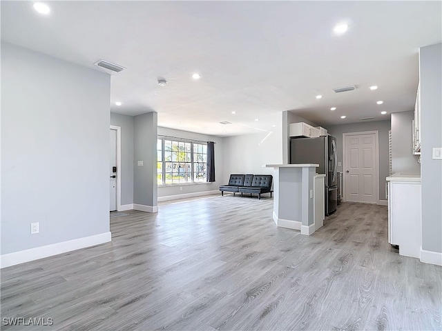 kitchen featuring light wood-type flooring, freestanding refrigerator, open floor plan, and visible vents