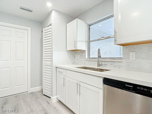 kitchen featuring tasteful backsplash, visible vents, dishwasher, white cabinetry, and a sink