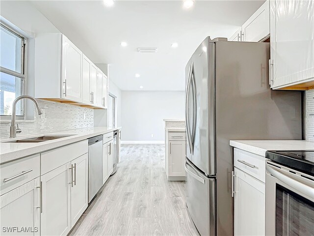 kitchen with appliances with stainless steel finishes, backsplash, a sink, and light countertops