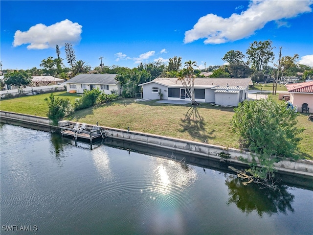 rear view of house with a lawn, a water view, and fence