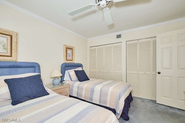 bedroom featuring ceiling fan, visible vents, multiple closets, carpet, and crown molding