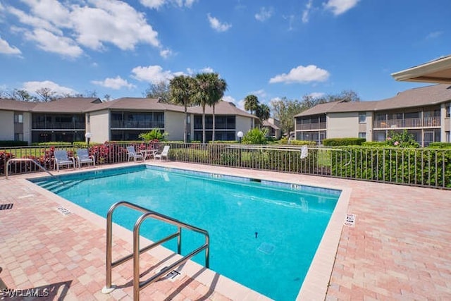 community pool with a residential view, fence, and a patio