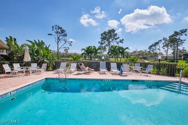 community pool with fence and a patio