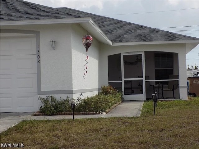 property entrance with roof with shingles, an attached garage, a lawn, and stucco siding