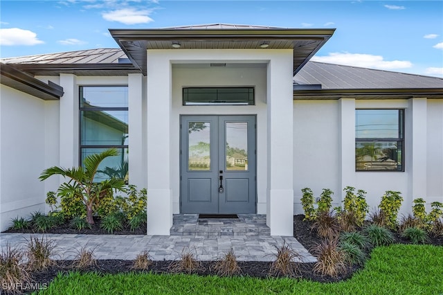 doorway to property featuring metal roof, french doors, a standing seam roof, and stucco siding