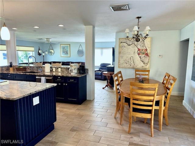 kitchen featuring visible vents, dishwashing machine, wood tiled floor, stone counters, and a sink