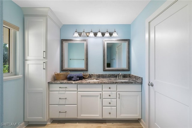 bathroom with double vanity, a sink, and wood finished floors