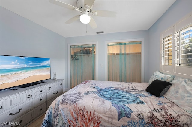 bedroom featuring ceiling fan, visible vents, and two closets