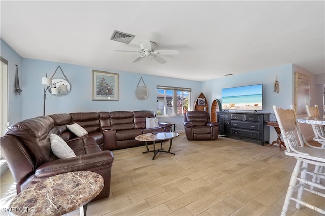 living room featuring light wood-type flooring, visible vents, and a ceiling fan